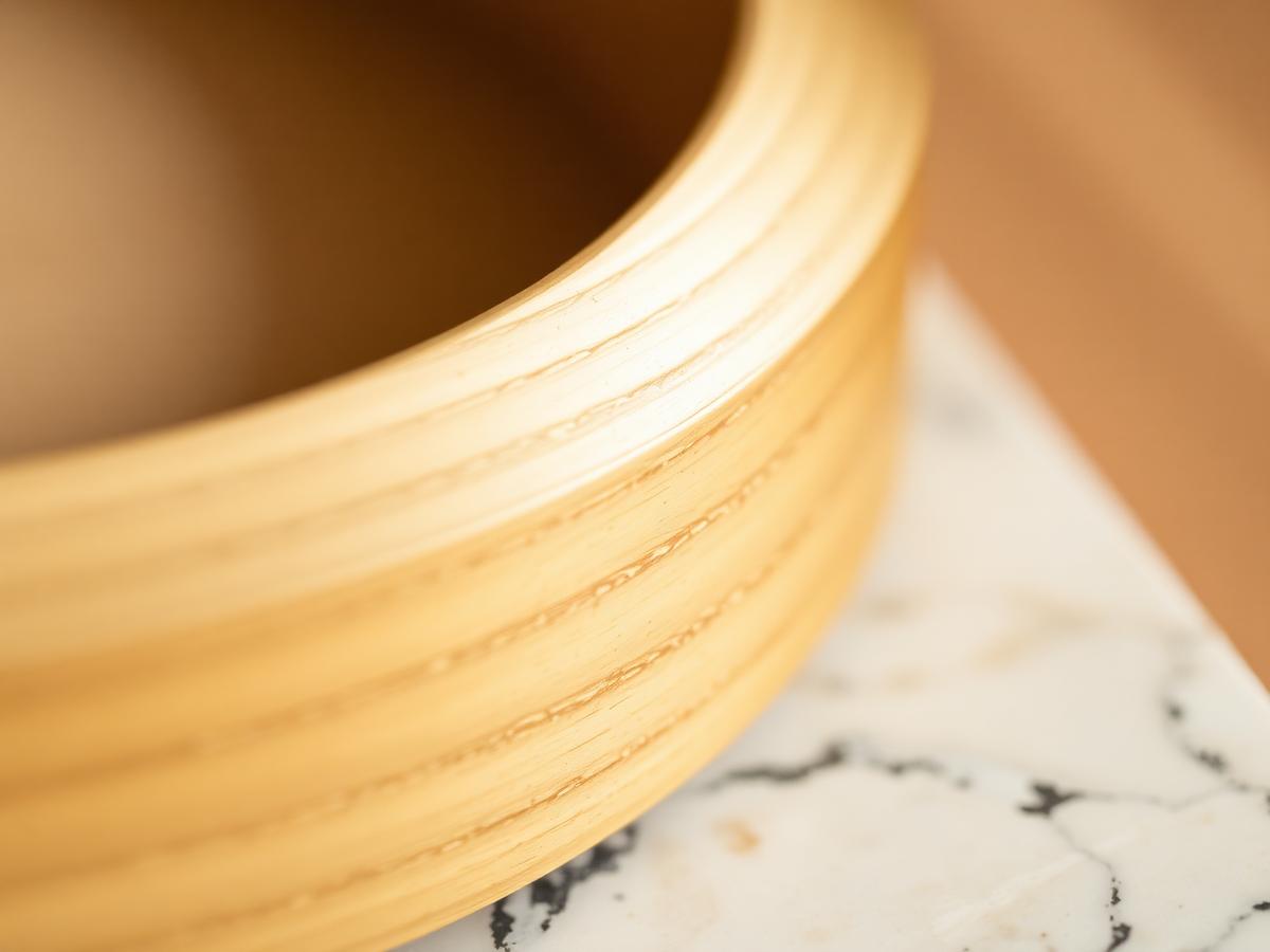 Macro detail of brushed brass meeting solid oak on a Nordé lamp