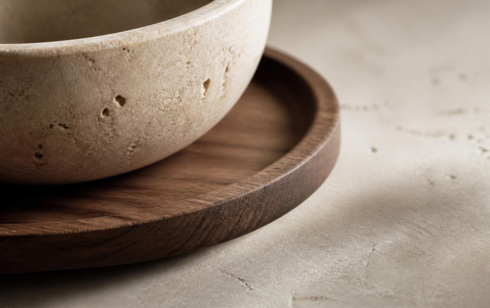 Close detail of a travertine stone bowl resting on a walnut wood tray