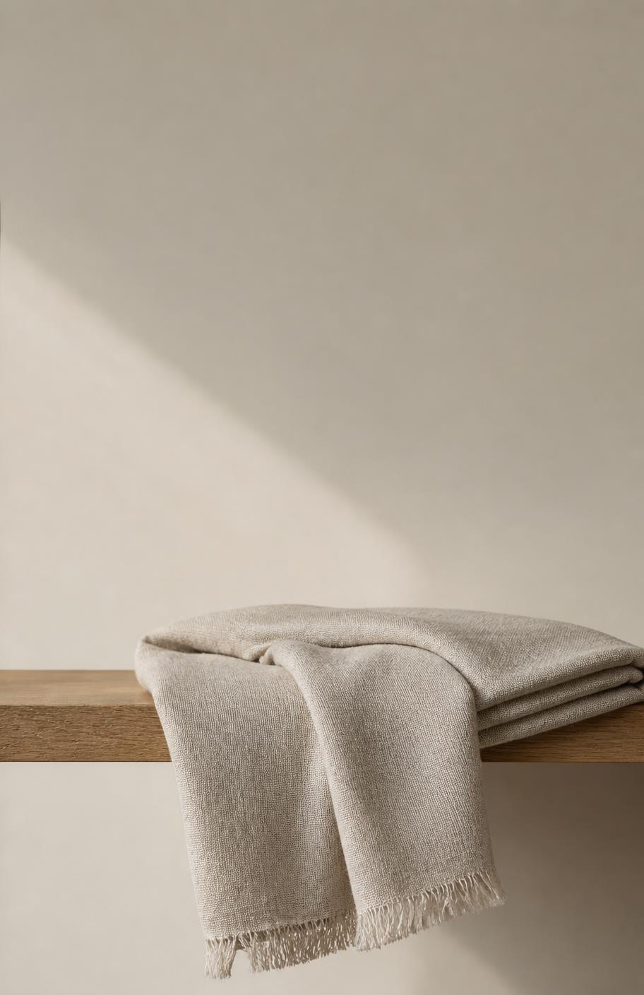 Folded natural linen textiles stacked on a travertine shelf
